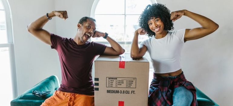 A man and woman sitting near a box waiting for local movers Connecticut